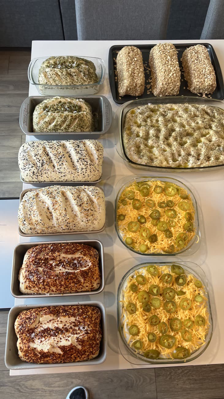 A counter covered in a morning's bake: seeded loaves, focaccia, and jalapeno cheese dips