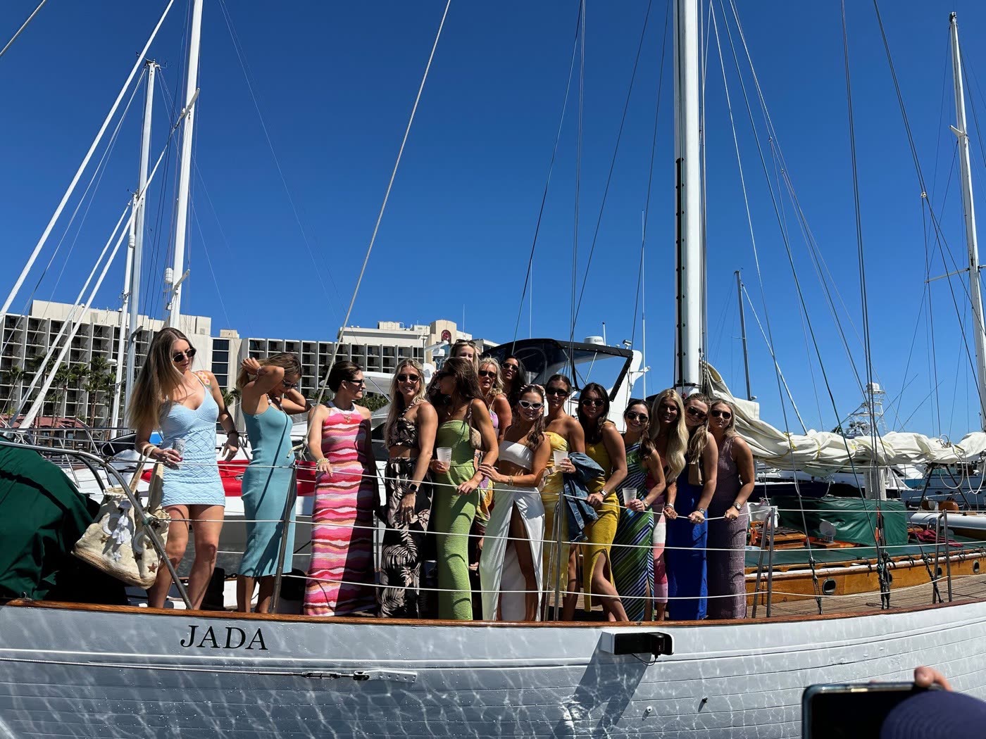 Guests lined along the rail of JADA, a white 1938 yawl, on a bright San Diego day