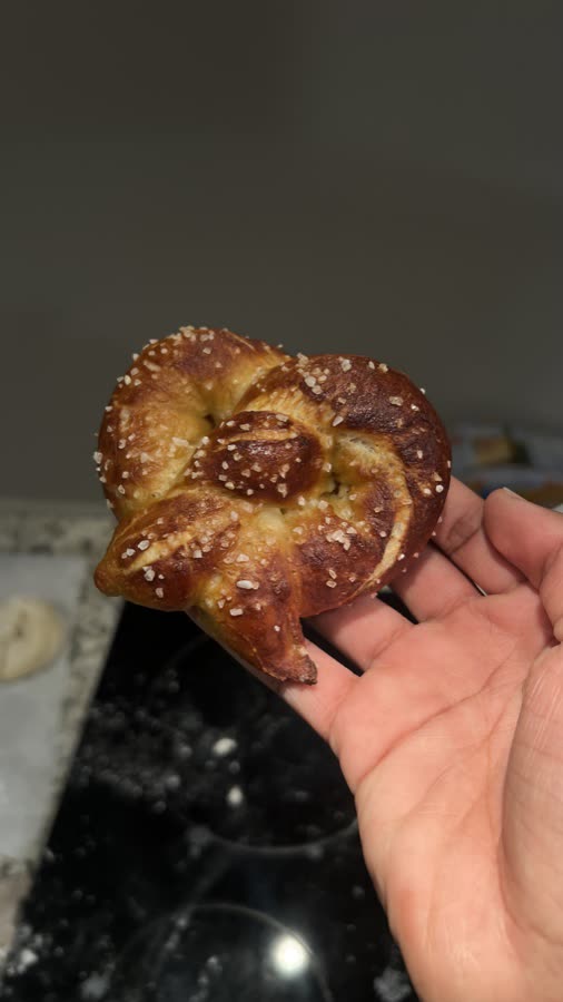 A hand holding a salted soft pretzel